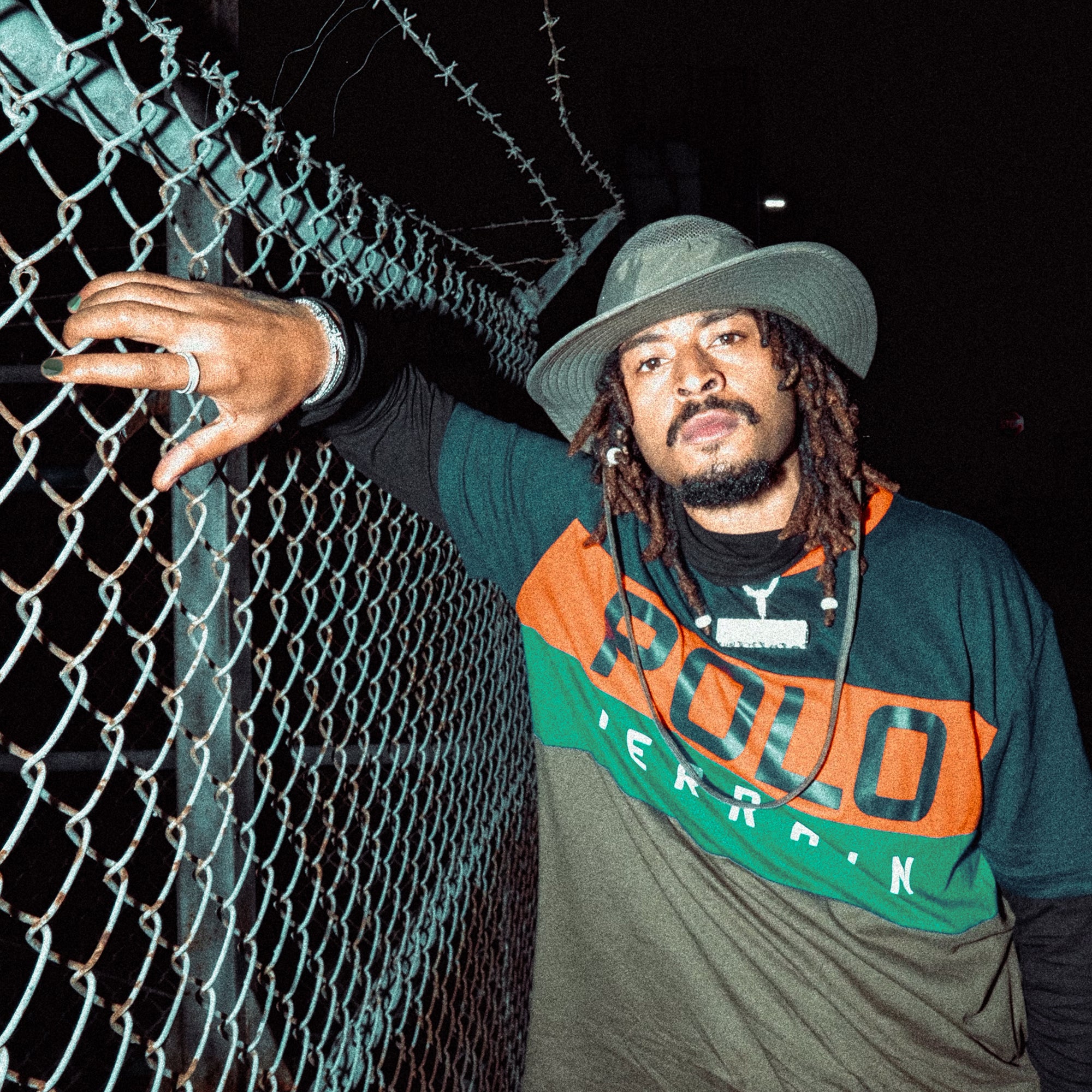 Man leaning on metal fence at night wearing the Maverick Duo.